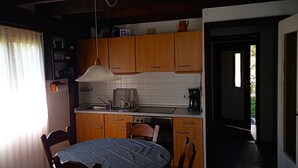 A kitchen with wooden cabinets, a sink, a stove, and a dining table with chairs. - Vacation apartment type C/Salzburg (Siegsdorf)