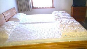 A bed with a wooden headboard, a window with curtains, and a wooden nightstand. - Vacation apartment type C/Salzburg (Siegsdorf)