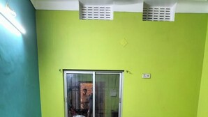 Una habitación con cama, ventana, una silla roja y pared verde.