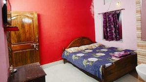 Ein Schlafzimmer mit einem hölzernen Bett, einer roten Wand, einem Deckenventilator, einer Klimaanlage und einem Fenster mit Vorhängen.