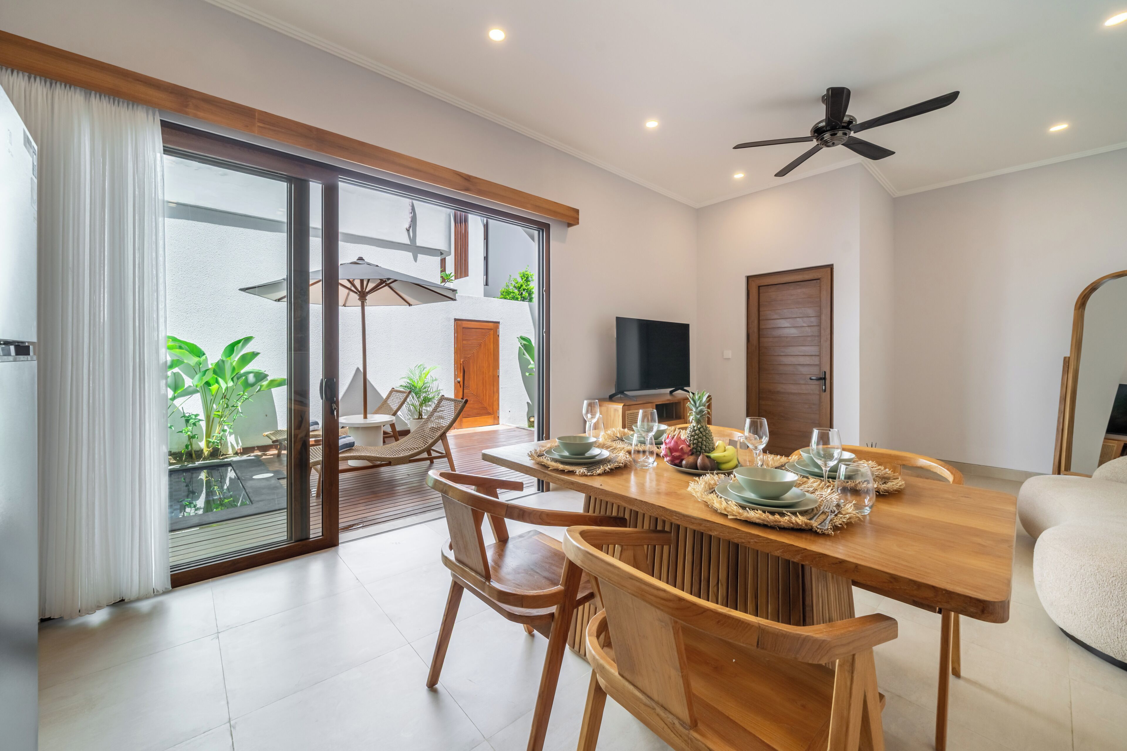A modern dining area with a wooden table, chairs, and a TV.