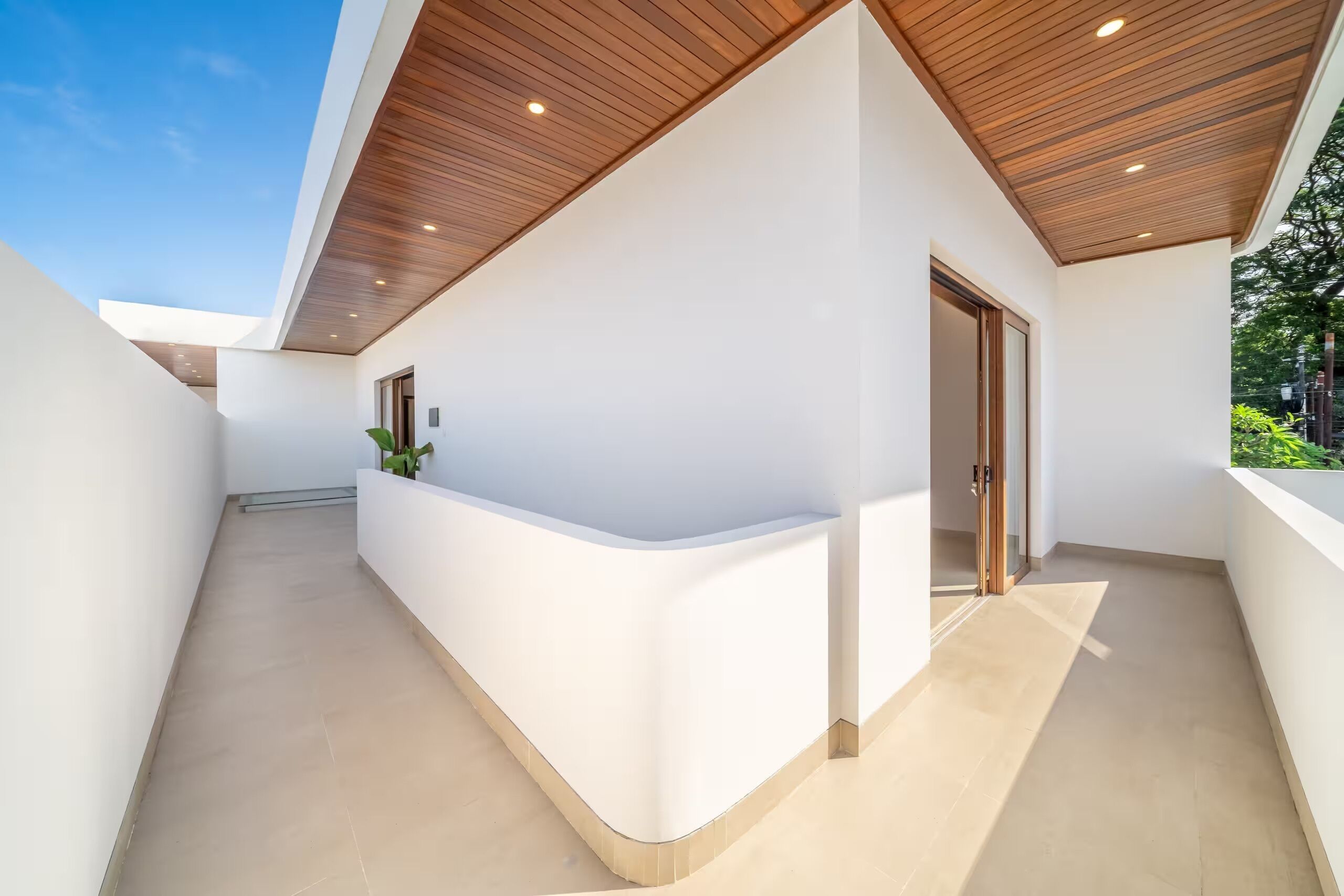 Un edificio moderno con una pared blanca curva, techo de madera y una puerta.