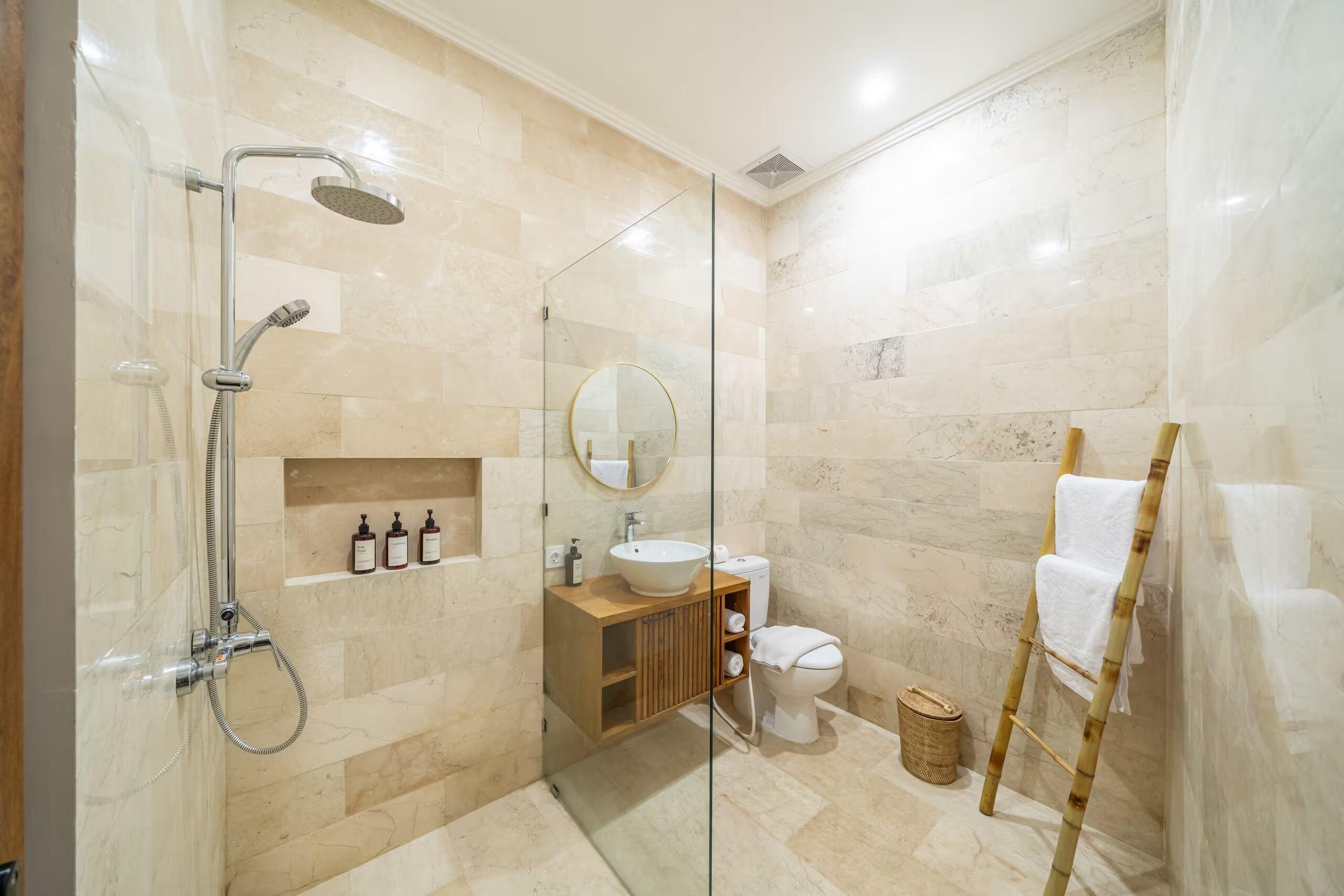 A modern bathroom with a glass shower enclosure, a wooden vanity, a toilet, and a towel rack.