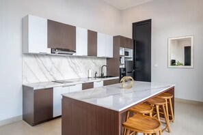 Una cocina moderna con encimera de mármol, taburetes de madera y una puerta negra.