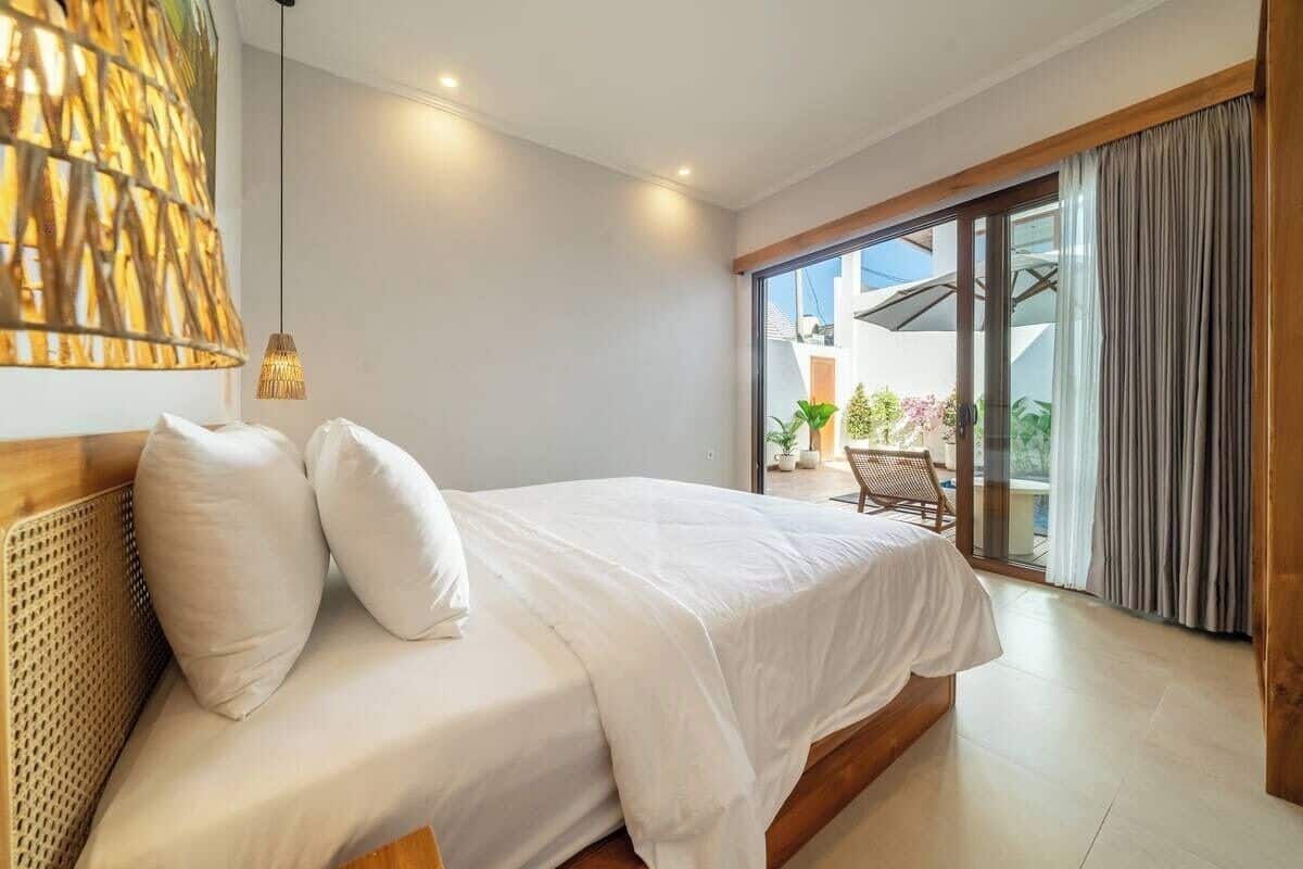 Un dormitorio con una cama, una lámpara colgante y vistas al exterior.