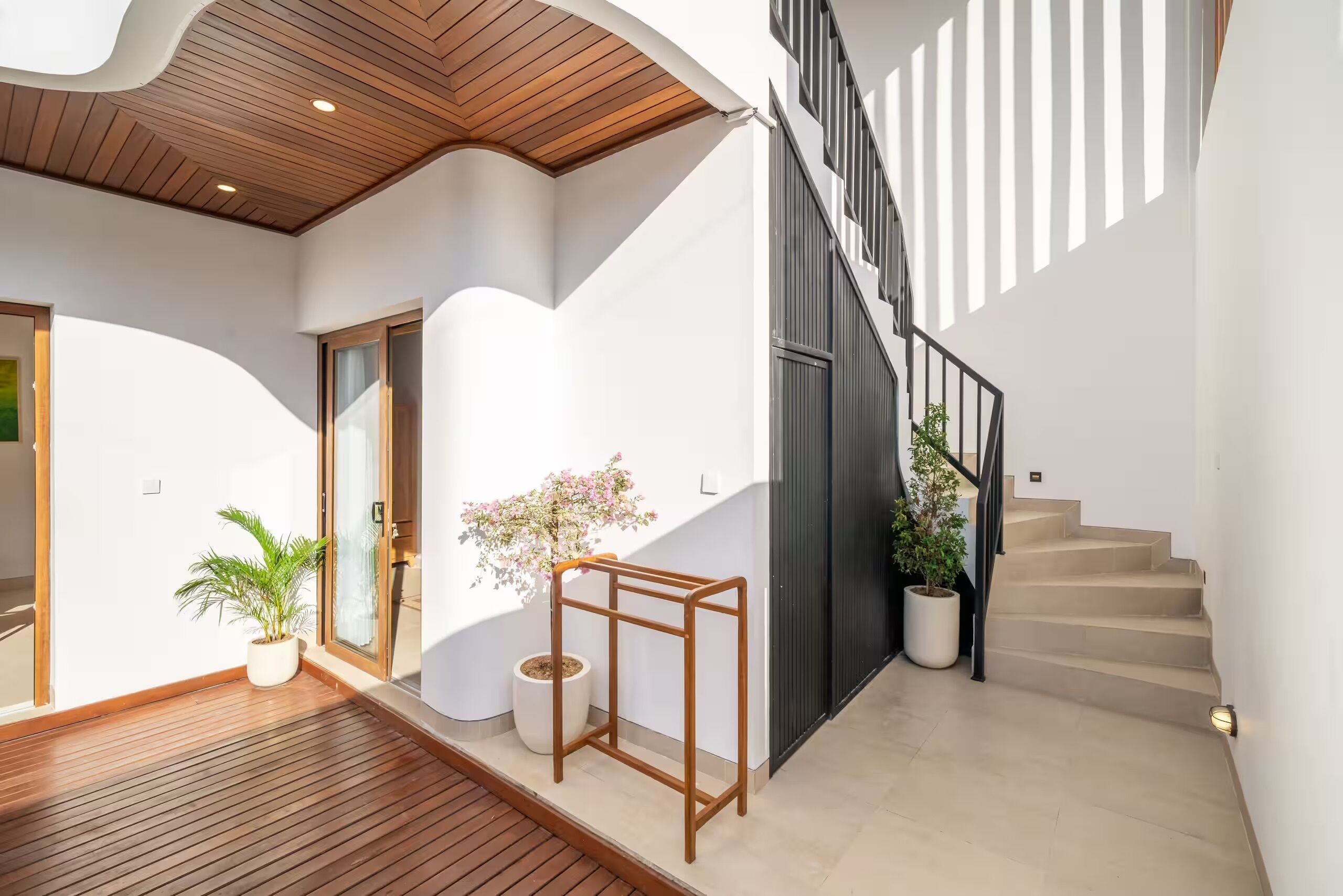 A modern interior with a wooden ceiling, a staircase, and potted plants.