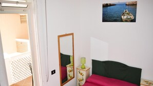 A bedroom with a bed, a nightstand with a lamp, a mirror, and a picture on the wall. - Casa vacanze Ureshii a San Foca (San Foca)