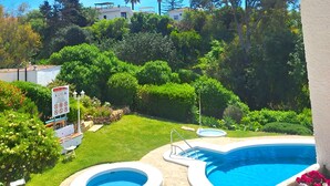 Un jardin avec deux piscines, un patio couvert et une végétation luxuriante tout autour.