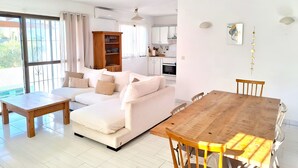 Un salon avec un canapé, une table en bois et une cuisine en arrière-plan.