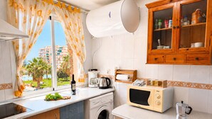 Een kleine keuken met een wasmachine, een magnetron en een koffiezetapparaat.