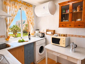 A compact kitchen with a washing machine, a microwave, and a coffee maker. - Lentiscares 213 Beach & Pool – Torrox Costa (Torrox Costa)