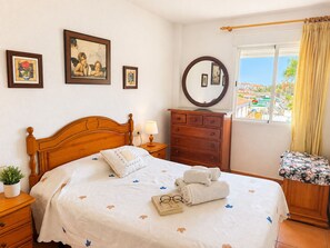 Un dormitori amb un llit de fusta, una petarrera, un mirall i una finestra amb vista a l'exterior.