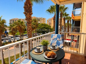 A balcony with a table set for two, featuring a plate of pastries, a cup, and a small plant. - Lentiscares 213 Beach & Pool – Torrox Costa (Torrox Costa)