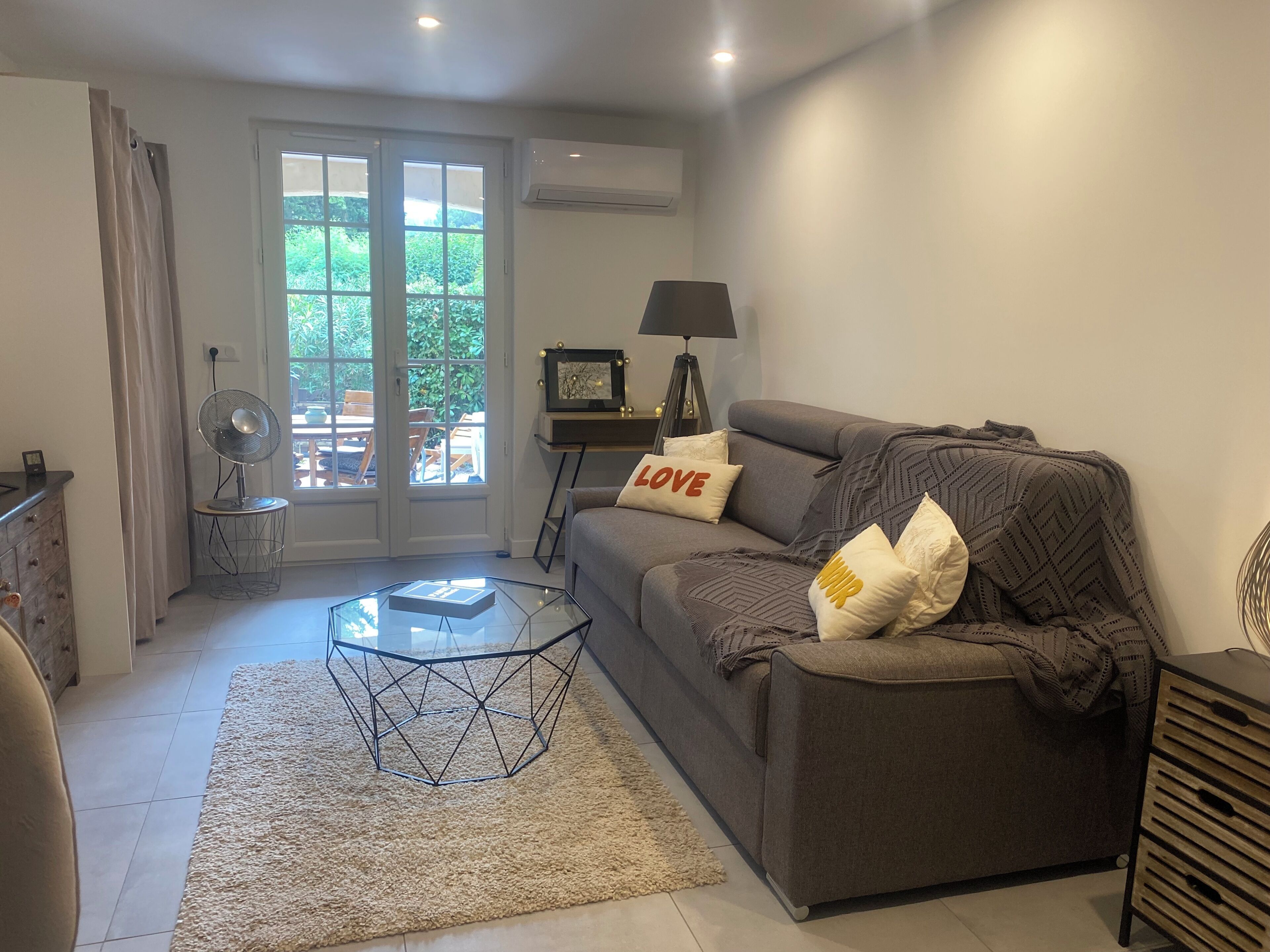 Ein Wohnzimmer mit Sofa, Couchtisch, Lampe und Ventilator.