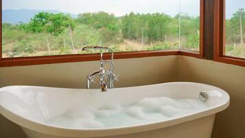 A bathtub with a view of a natural landscape through a window.