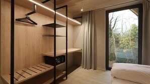 A bedroom with a bed, a wardrobe with shelves, a mirror, and a window with curtains. - Woodz Lodges - Groepslodge | 10p (Heusden-Zolder)