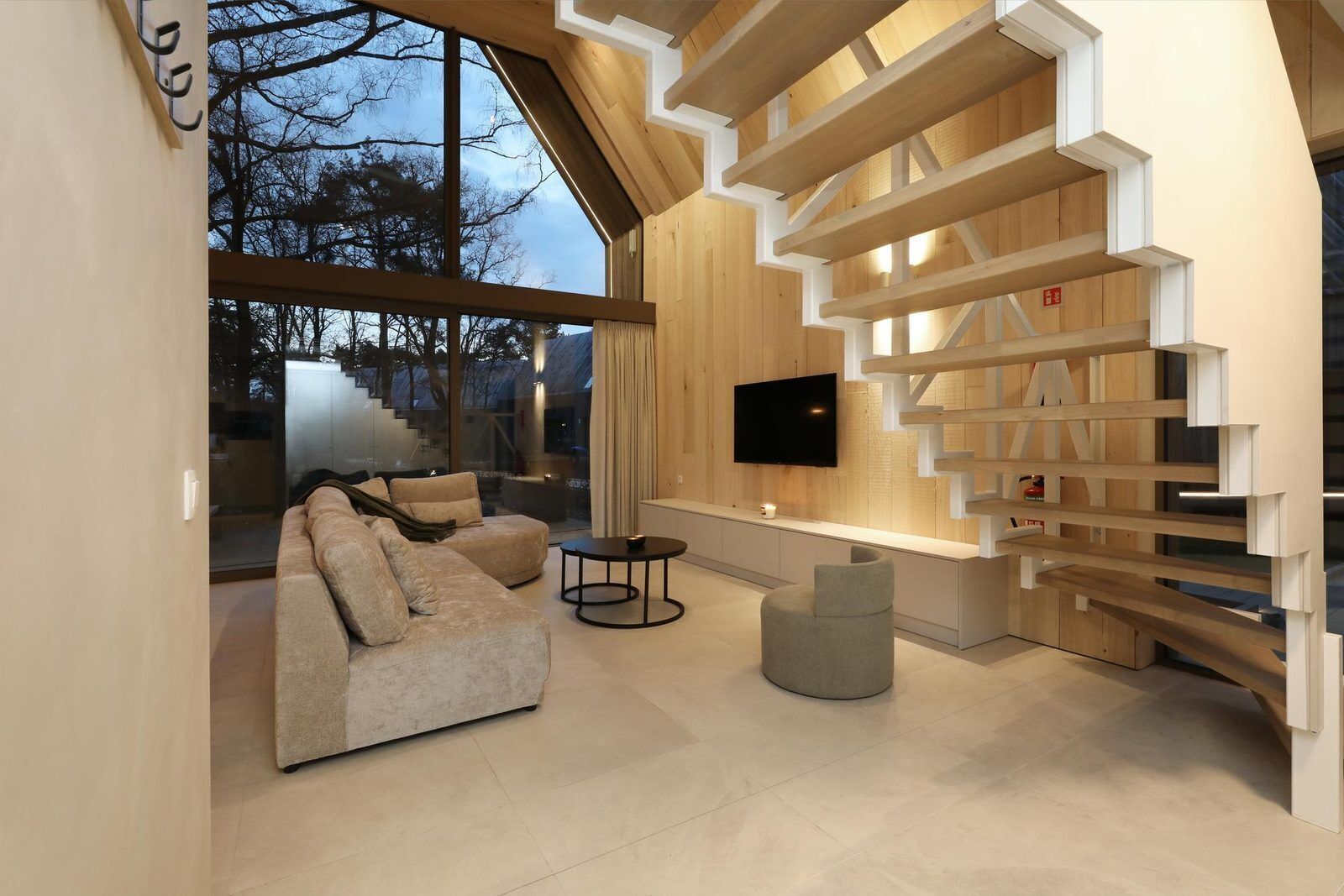 A modern interior with a sofa, a TV, and a unique staircase design.