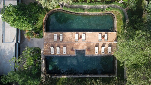 Vue aérienne d’une piscine dotée d’une terrasse ensoleillée et de chaises longues.