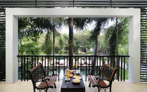 Ein Balkon mit Tisch für zwei Personen, umgeben von üppiger Vegetation und Palmen.