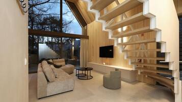 A modern interior with a sofa, a TV, and a unique staircase design.
