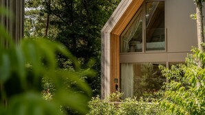 A modern building with large windows, surrounded by lush greenery.
