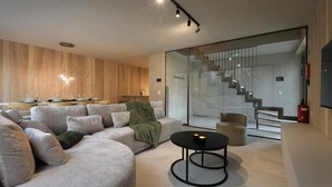 A modern living room with a sectional sofa, a round coffee table, and a staircase leading to an upper floor.