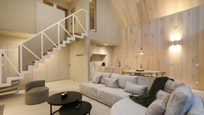 A modern interior with a staircase, a sofa, a coffee table, and a dining area.