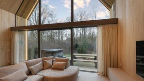 A modern interior with a curved sofa, large windows, and a view of the outdoors.