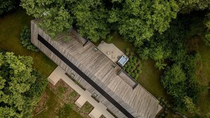Vista aérea de un edificio moderno con una estructura larga y estrecha, rodeado de abundante vegetación.