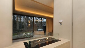 Un interior moderno con chimenea de vidrio, zona de estar y ventanas amplias.