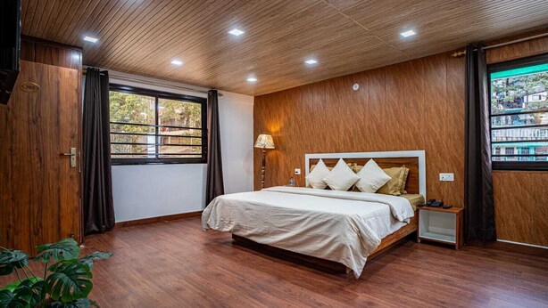 Une chambre avec un plafond en bois, un lit doté d’une tête de lit blanche, une lampe de chevet et une fenêtre avec des rideaux.