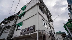 Un immeuble à plusieurs étages, sur lequel on peut lire l’enseigne « PPEAKS PINES », ce qui indique qu’il s’agit d’un établissement commercial.