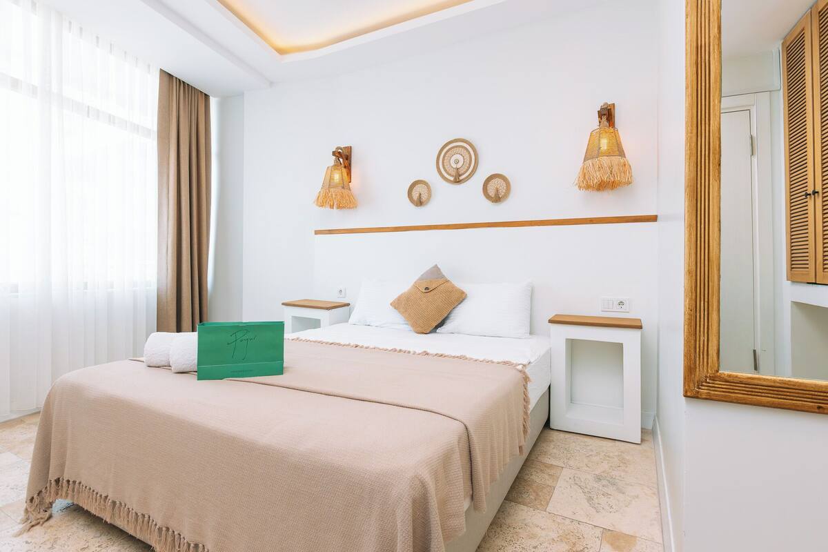 A hotel room with a bed, bedside tables, a mirror, and wall decor.