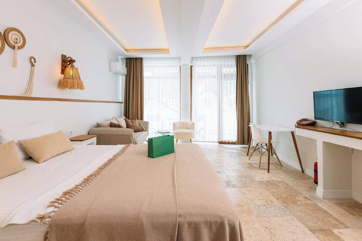 A hotel room with a bed, a desk, a TV, and a chair.