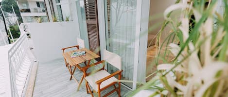 A balcony with a wooden table and chairs, a glass door, and a view of the surrounding buildings.