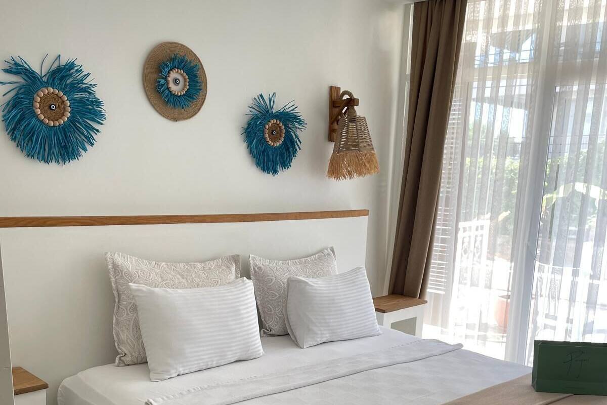 A neatly made bed with a white and beige bedspread, a brown throw blanket, and decorative wall art.