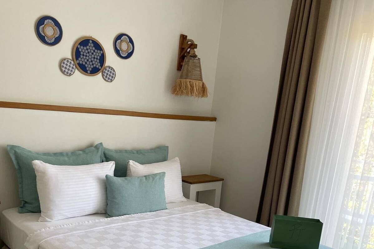 A neatly made bed with a checkered bedspread, a green throw blanket, and multiple pillows.