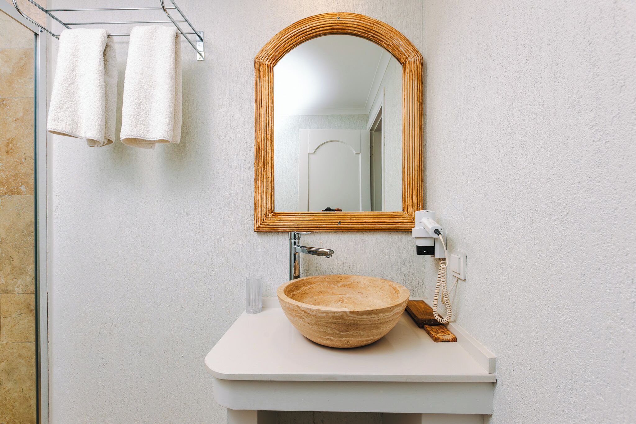 A bathroom with a wooden bowl sink, a white countertop, a mirror, and a telephone.