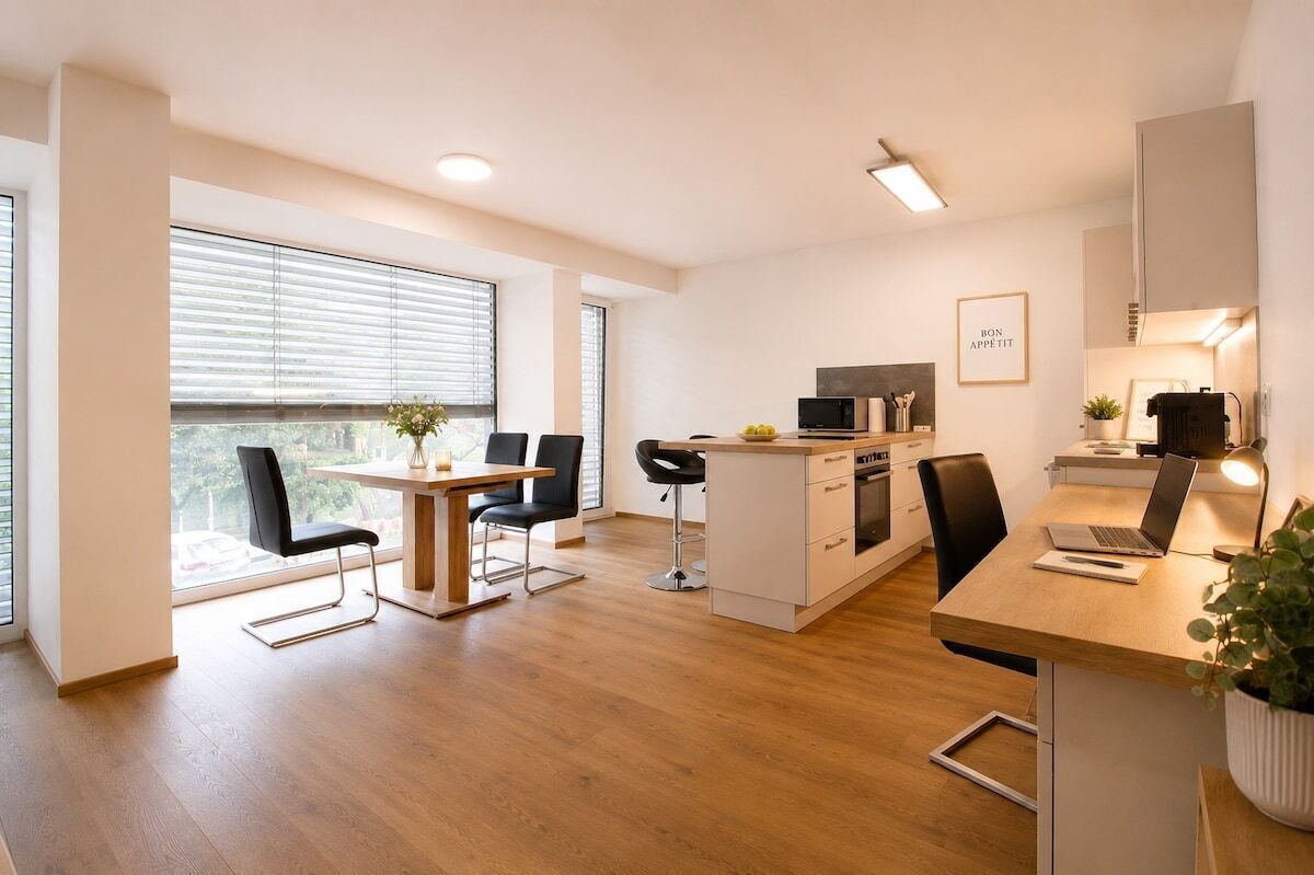 A modern kitchen with a dining area, a microwave, and a laptop on the counter.