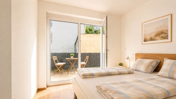 Un dormitorio con una cama, una ventana y una puerta que da a un balcón.