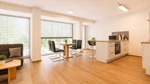 Un apartamento moderno con comedor, kitchenette y un sofá con mesita de centro.