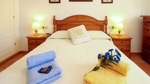 Un llit ben fet amb dos coixins, dues taules de nit amb làmpades i un taulell de fusta.