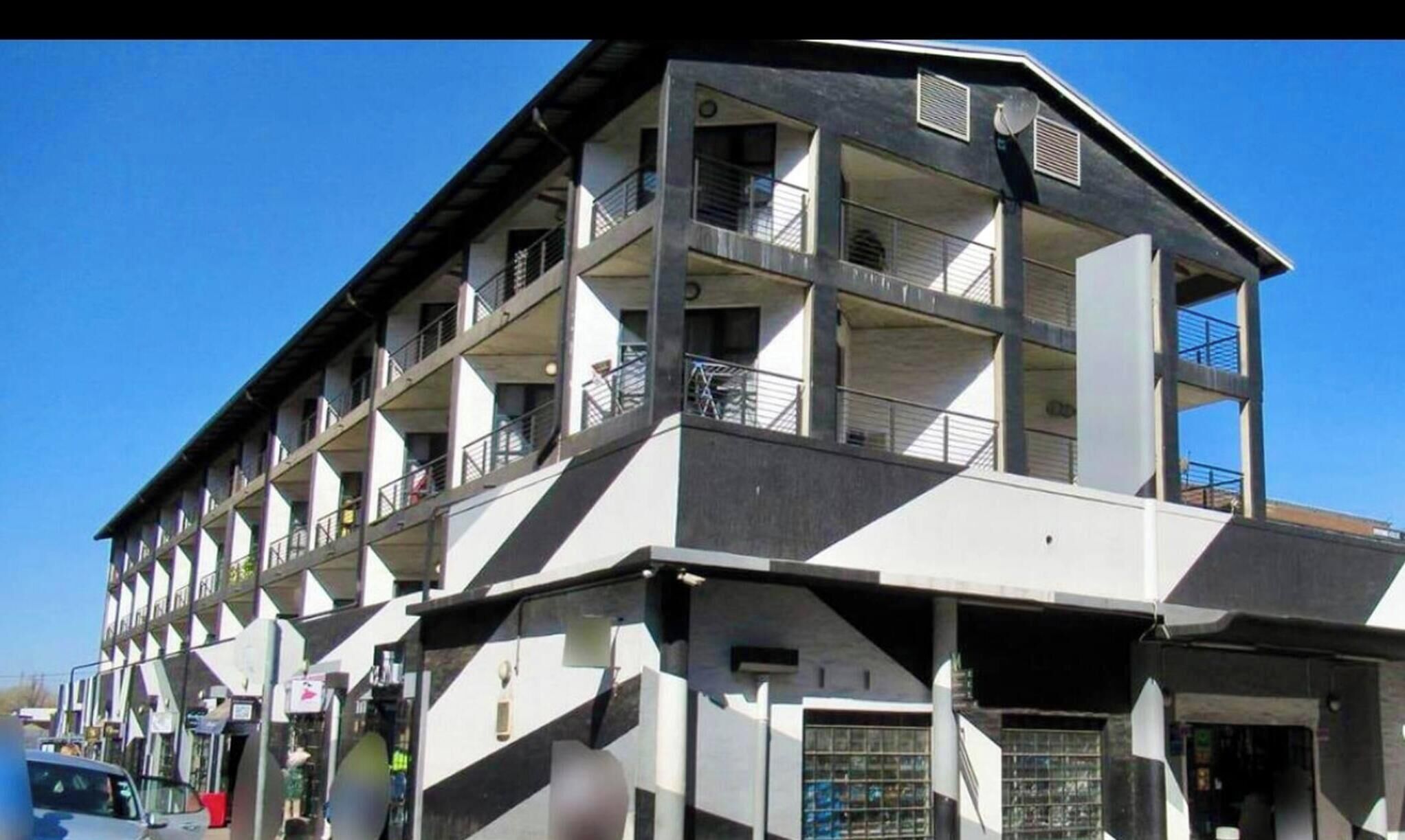 A multi-story building with balconies, a flat roof, and a ground-level entrance.