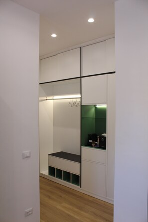 A walk-in closet with a bench, shelves, and a green-lit section. - Da Rosalia Apartment: all the comforts in the heart of Palermo's historic center (Palermo)
