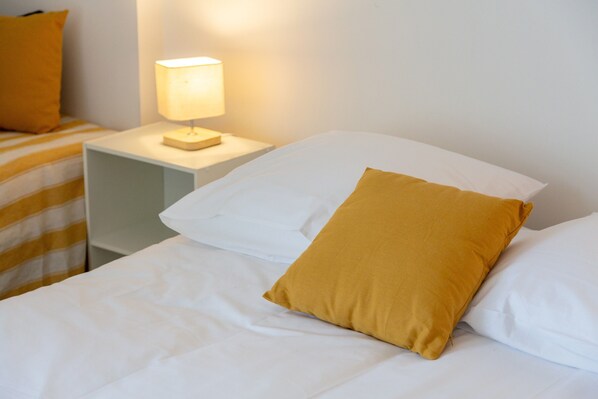 Une chambre d’hôtel avec un lit, une table de chevet avec une lampe et une couverture à rayures.
