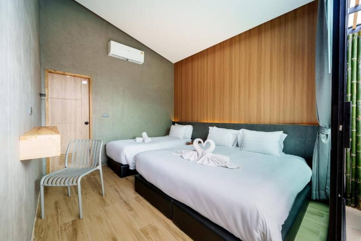 A hotel room with two beds, a wooden panel wall, a chair, and a door.