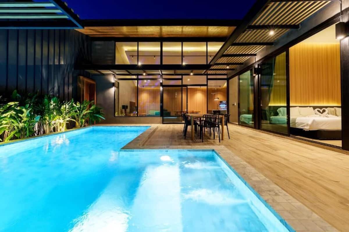A modern house with a swimming pool, a dining area, and a bedroom with a large window.
