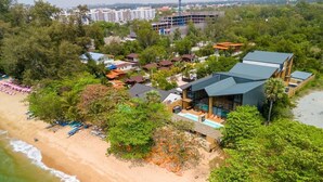 An aerial view of a coastal resort with beachside villas, a swimming pool, and a beach with umbrellas. - Dojo poolvilla beach resort (Sattahip)