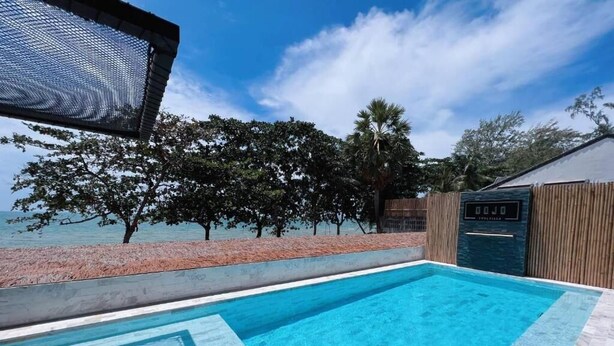 A swimming pool with a view of the sea, surrounded by trees and a wooden fence. - Dojo poolvilla beach resort (Sattahip)