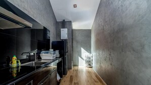 A modern kitchen with a black countertop, stainless steel appliances, and a visible water heater. - Dojo poolvilla beach resort (Sattahip)
